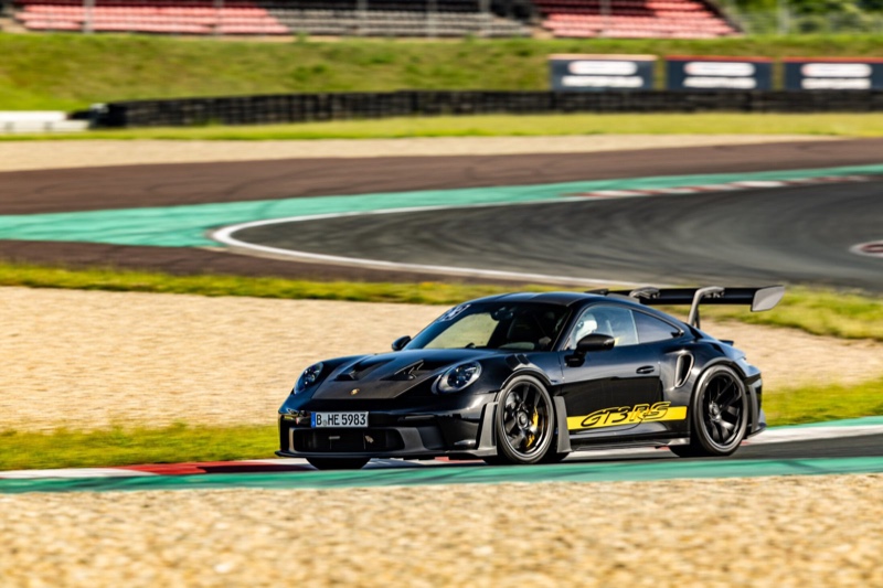Schwarzer Porsche 911 GT3 RS mit gelber Beklebung in schneller Fahrt auf einer Rennstrecke