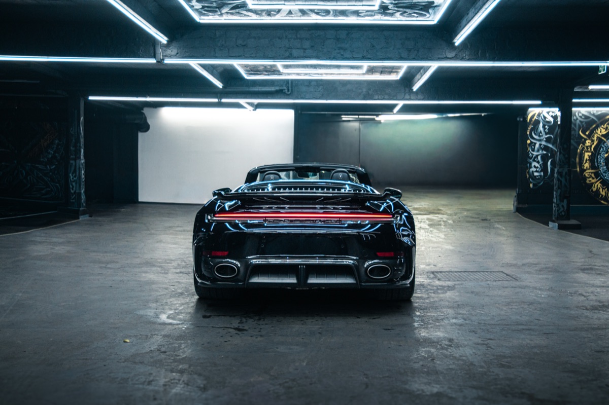 Porsche 911 Turbo S Cabriolet mit geöffnetem Verdeck von hinten in einer Halle mit LED-Deckenrahmen